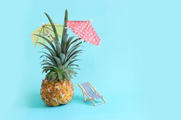 Image with ripe pineapple with parasol and beach chair over blue background. Summer holidays and...