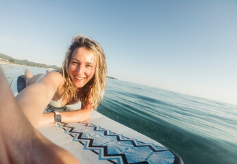Smiling woman taking self portrait on paddle board