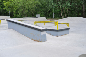 figures in a concrete skateboard and bmx park against the background of green trees