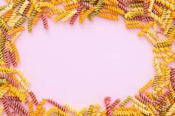Beautiful Italian uncooked colored farfalle pasta close-up on pink background. horizontal top view