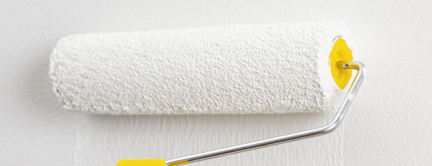 Hand of a female with paint roller. Painting apartment, renovating with white color paint.