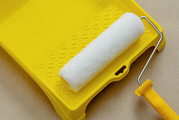 Paint roller in paint tray with white color. Repair and painting in the house. Construction and painting works.
