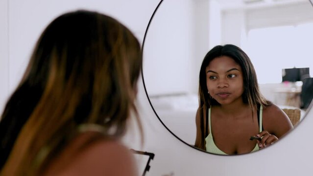 Young hispanic latina woman applying makeup in her bedroom - Teenager female putting painting eyelashes before going on party
