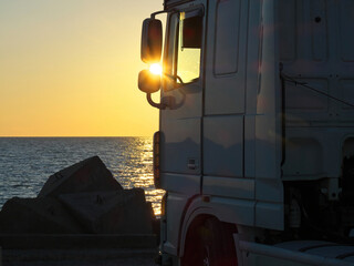 Scenic view  truck. Truck on the breakwater. Warm morning evening sunrise sun sky sunset.