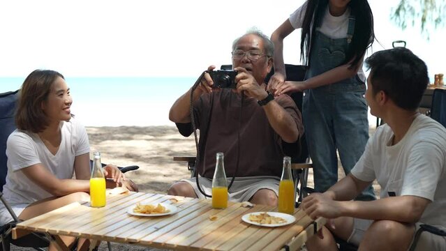 Happy family grandfather senior looking picture in camera taking memories outside on the beach camping together fun and enjoy life.