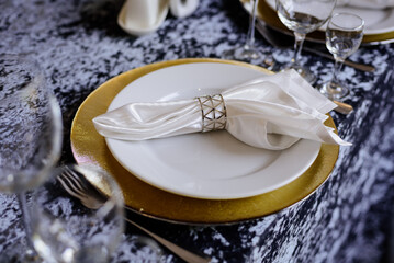 White plates, silver cutlery, glasses on the table with a velvet tablecloth.	