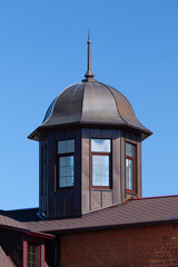Small tower with spire on the roof under blue sky. Church exterior