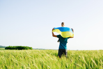 son with father in a field with Ukrainian flag