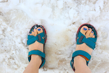 feet of a girl in sandals in the snow