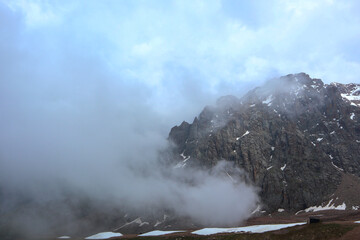 clouds and fog on top of mountains. rocky mountains with snow. stunning landscape           