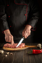 Chef cuts raw veal meat on a cutting board before baking. Cooking delicious food in the kitchen