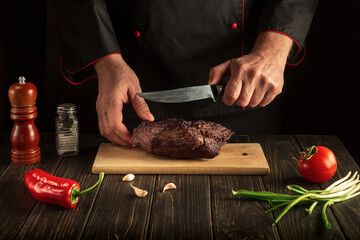 Slicing baked beef meat on a cutting board. The idea of preparing a delicious lunch by a chef. Copy space for text menu or recipe