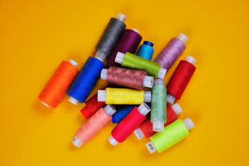 Spools with multicolored threads on a yellow background. Blurring background.