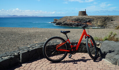 Bicycle on seafront promenade with sea, cliffs and Martello tower in background.