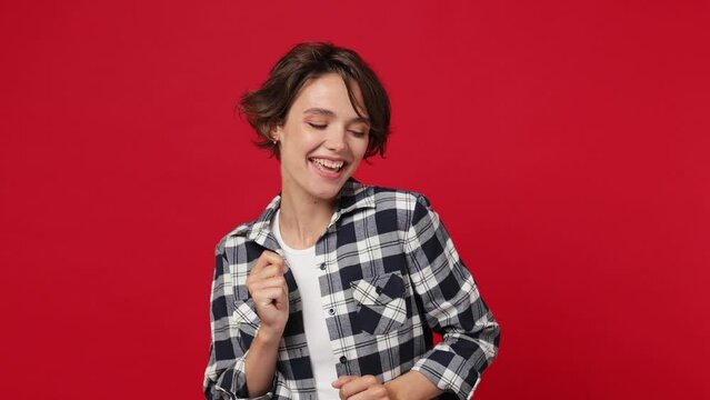 Young woman 20s she wearing casual clothes dance waving gesticulating hands fool around have fun enjoy snap her fingers to music rhythm isolated against over plain solid dark red color wall background
