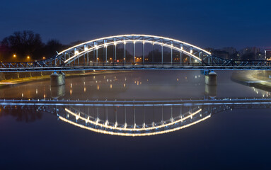 Fototapeta na wymiar Pilsudski steel truss bridge over Vistula river in Krakow in the night