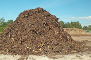 a product of wood processing, in the photo mountains of wood chips and sawdust against a blue sky