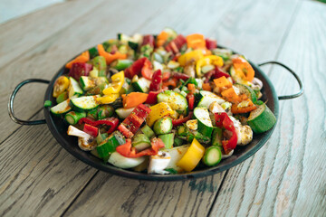  Grilled vegetables in a pan on a wooden table in the backyard of the house at summer. Vegan, vegetarian, seasonal, healthy eating diet concept. 