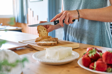 Woman making summer strawberry sandwich. Female hands cutting bread for toast. Healthy eating, fruit dieting brunch.