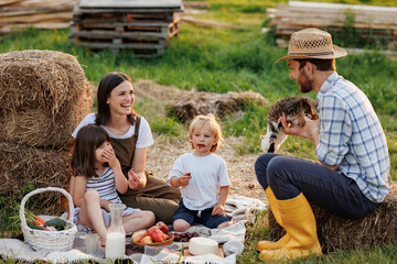 Happy young family having lunch at summer garden party. Mother, father and two kids enjoy spending...