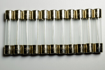 Small pile of clear electrical fuses on a white background. Set of glass fuses with filament inside. Macro picture. Current protection for electric circuits.
