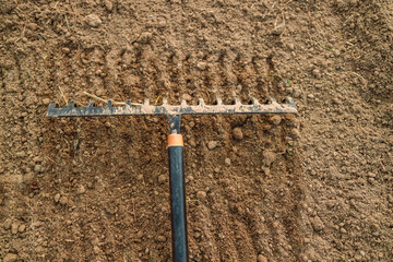 Loosening the soil with a rake in the greenhouse. Close up of an new metal garden rake cleaning...