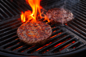 Barbecue wagyu beef Hamburger grilled as close-up on a charcoal grill with fire and smoke
