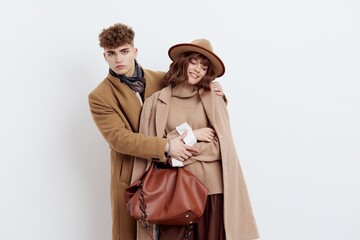 a happy couple in love is standing in beige stylish autumn coats on a white background and a man is holding a woman's hands smiling pleasantly