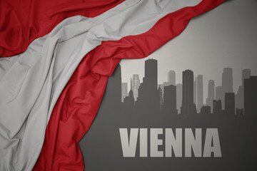 abstract silhouette of the city with text Vienna near waving national flag of austria on a gray...