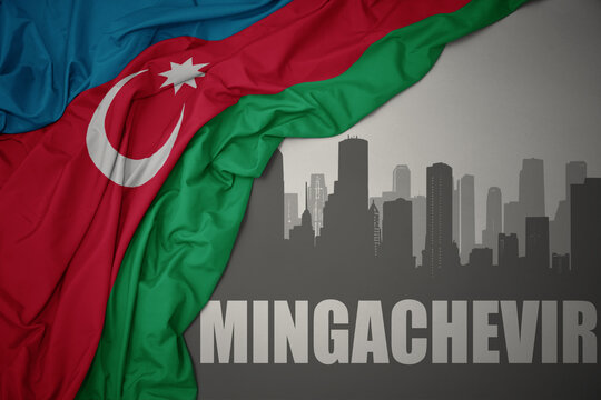 abstract silhouette of the city with text Mingachevir near waving national flag of azerbaijan on a gray background.