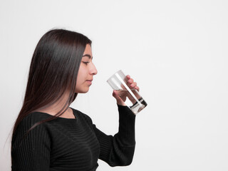 latina girl holding a glass of water, concept of hydration and how drinking 8 liters of water a day makes you look younger.