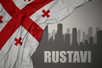 Fototapeta premium abstract silhouette of the city with text Rustavi near waving national flag of georgia on a gray background.