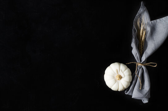 The concept of the background of autumn. White pumpkin and a faceted napkin with a spike on a black background