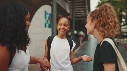 Three girls friends pre-teenage stand on the street smiling and emotionally talking, playing. Three teenagers on the outdoors in urban cityscape background - Powered by Adobe