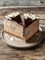 Two slices of chocolate cheesecake glazed with almond petals topping close up on wooden background
