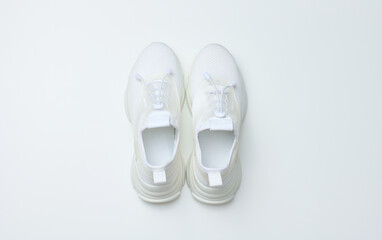 White textile sneakers on a white background, top view
