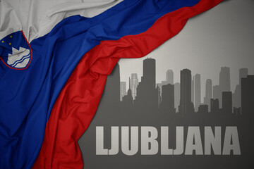 abstract silhouette of the city with text Ljubljana near waving national flag of slovenia on a gray background.