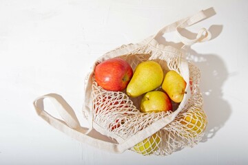 Mesh eco-friendly shopping bag with fruit on a white background. The concept of zero waste, fruit diet, healthy lifestyle.
