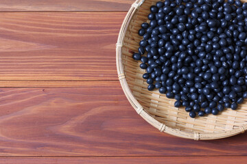 木材背景の笊にいれた黒豆
