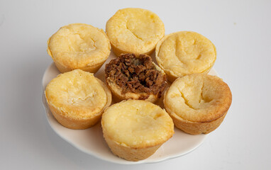 Yellow cream tarts on a plate with a pecan tart in the middle, white background