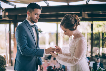 Wedding ceremony outdoors. The bride and groom put on each other's wedding rings