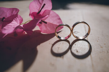 Bride's morning and wedding details. Wedding gold rings on a stone surface in bougainvillea flowers