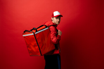 Delivery courier with red food backpack deliver food orders. Man delivering fast food with thermal backpack. Food delivery courier.