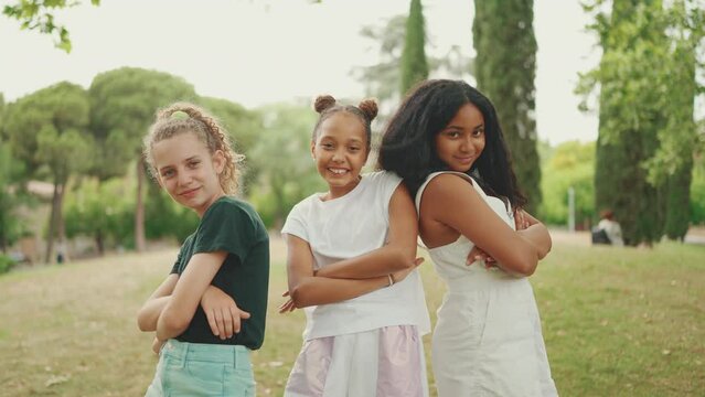 Smiling three girls friends pre-teenage cross their arms in dance move in the park