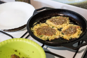 Potato pancakes with minced meat are fried in a cast-iron pan. Cooking at home