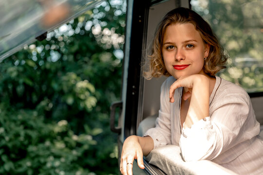 A young woman looks out of the trailer window at summer time