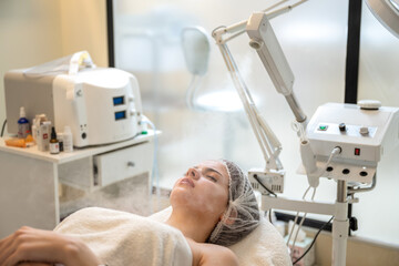 Beautiful woman on ozone therapy with facial steamer in beauty salon.