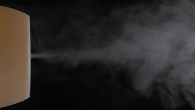 Diffuser for essential oils diffusing steam on black background. Nobody