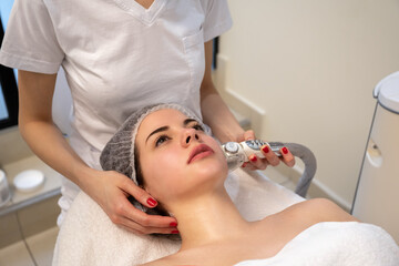Young female patient getting radio frequency lifting on her face in beaut salon.