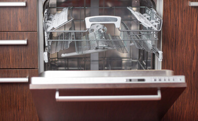 Open dishwasher in the kitchen. Dishes in the machine.